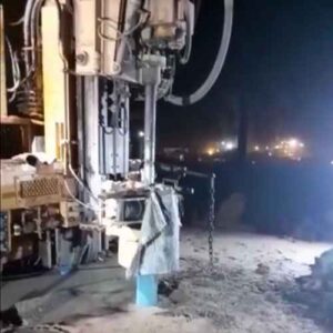 Close-up de um equipamento de perfuração de poços artesianos em operação noturna.